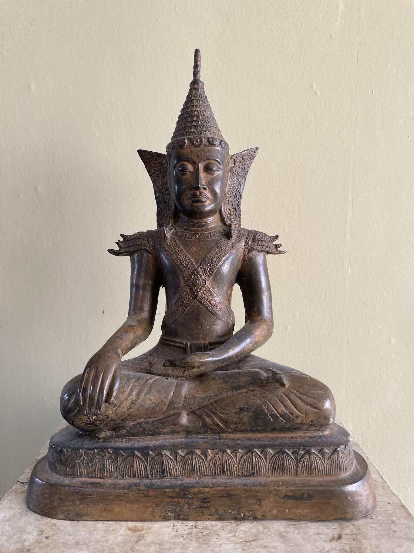 Raw smartphone snapshot of a Burmese bronze Buddha on a wooden surface